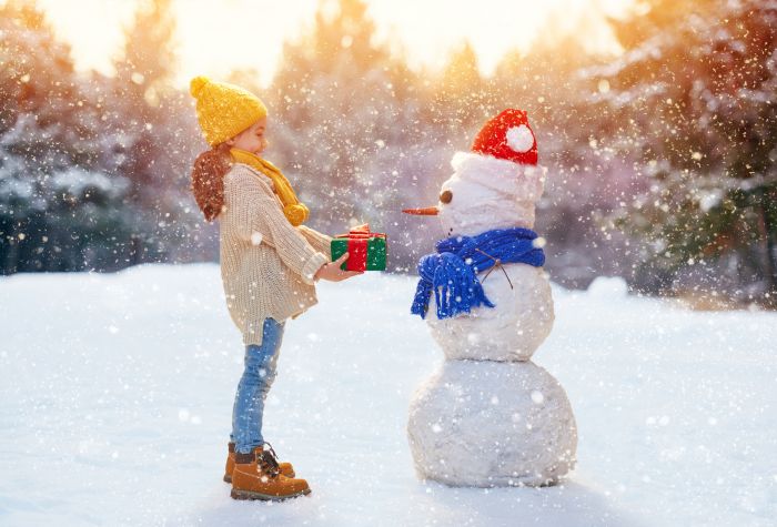 Картинка зима, падает снег, девочка дарит подарок снеговику