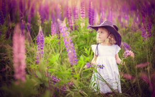девочка в шляпе на природе, ребенок среди растений люпин