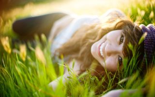 девушка с улыбкой лежит на траве