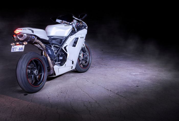 Картинка красивый белый мотоцикл Ducati 1198 стоит в темноте при свете фар