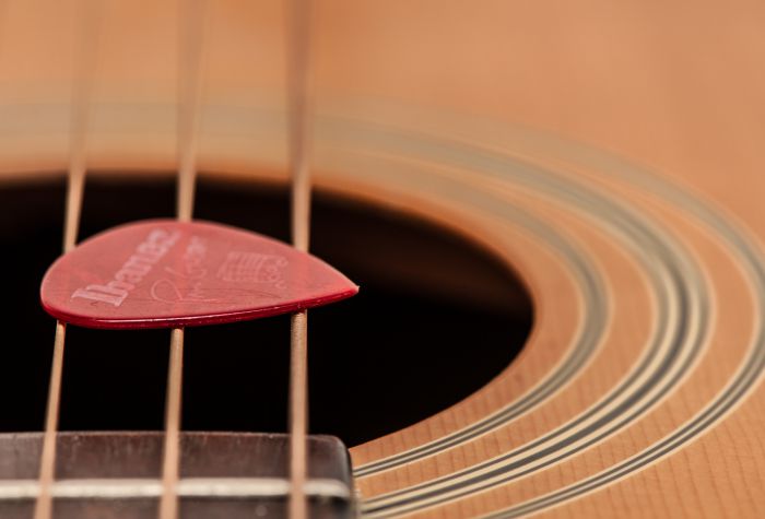 Картинка макро фото медиатор лежит на струнах гитары