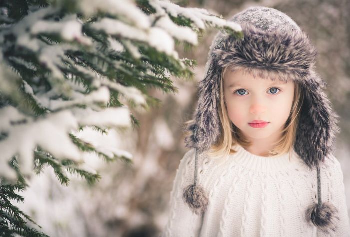 Картинка ребенок, девочка в шапке и свитере зимой возле елки