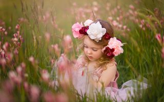 маленькая девочка, ребенок в венке из цветов сидит в траве