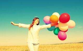 девушка с разноцветными воздушными шарами, стоит в поле