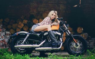 девушка блондинка в сапогах сидит на мотоцикле Харли-Дэвидсон