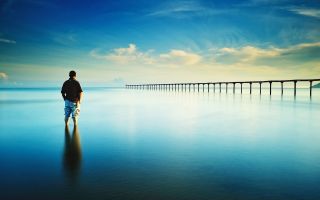 мужчина стоит в заливе перед мостом