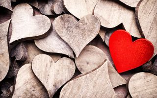 красное сердце лежит на деревянных сердцах