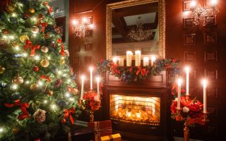 новогодняя елка с украшениями возле камина и свечек