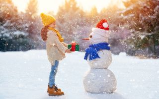 зима, падает снег, девочка дарит подарок снеговику