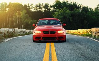красная машина BMW e90 стоит на середине дороги
